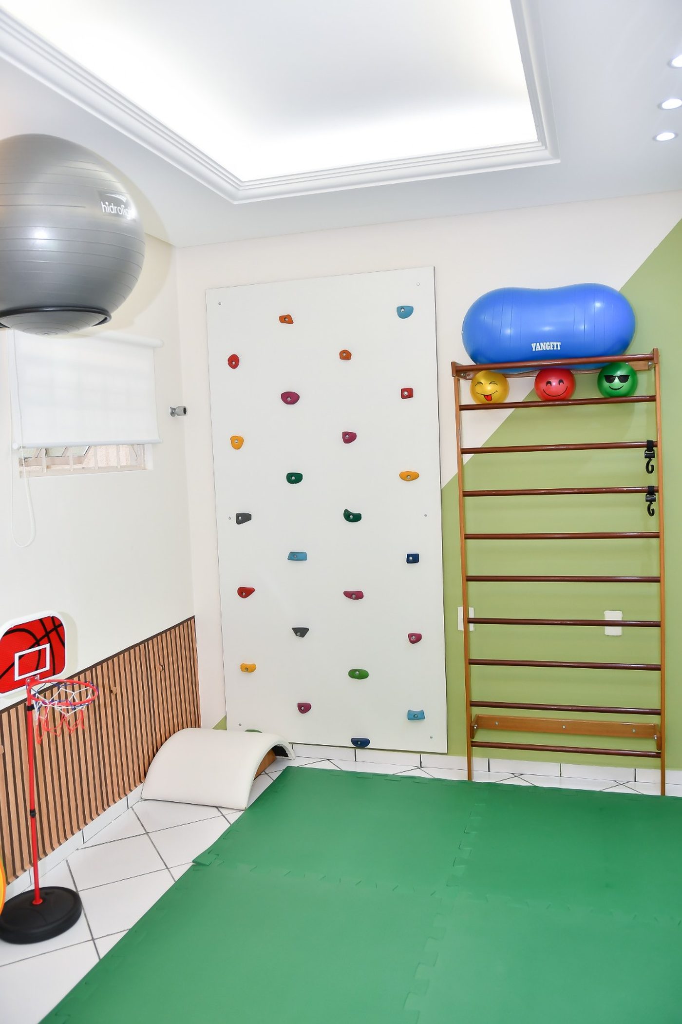 Sala lúdica de fisioterapia infantil com parede de escalada