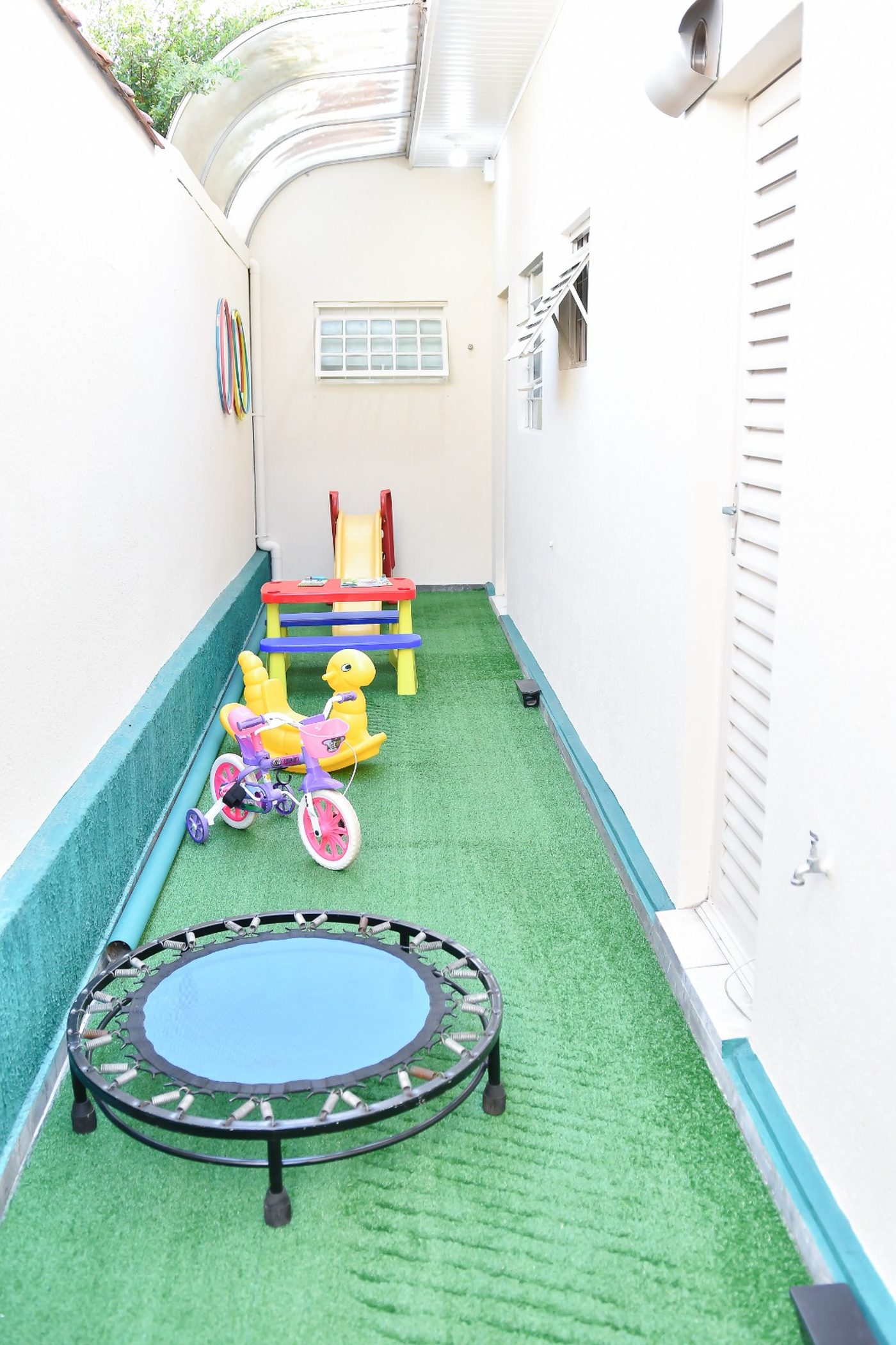 Área externa coberta com brinquedos e trampolim